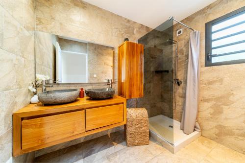a bathroom with two sinks and a shower at VILLA L HORIZON 4 appartements avec piscine in Petite Île