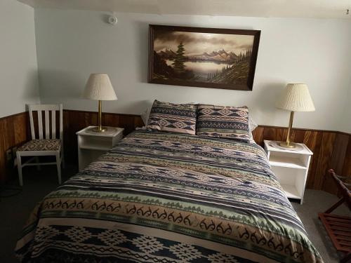 ein Schlafzimmer mit einem Bett mit zwei Lampen und einem Gemälde an der Wand in der Unterkunft Grandma's Home in the Woods. Yellowstone in Island Park