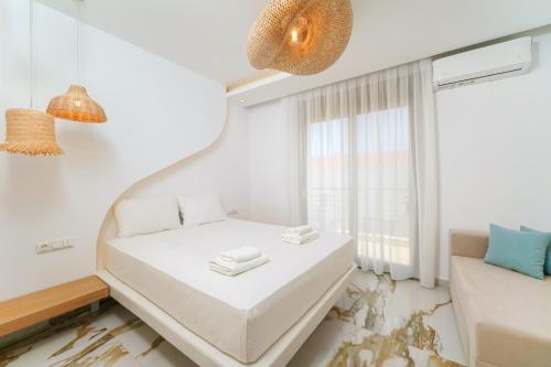 Cette petite chambre blanche dispose d'un lit et d'une fenêtre. dans l'établissement Athina Palace Luxurious Appartments, à Potos