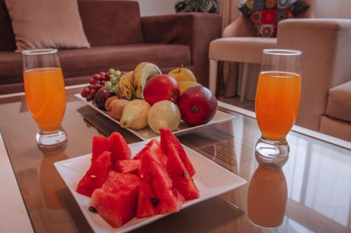 a table with a plate of fruit and two glasses of orange juice at Swiss Royal DAHAB in Dahab