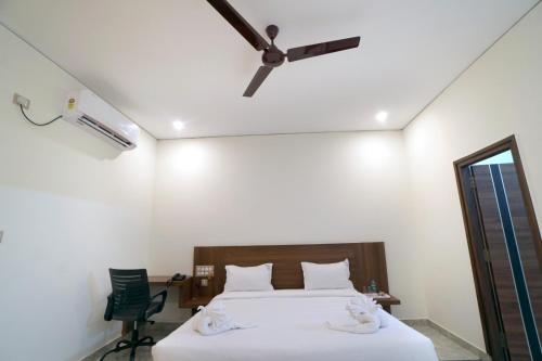 a bedroom with a bed and a ceiling fan at KCG Residency in Mysore
