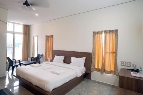 a bedroom with a large bed and a desk and chairs at KCG Residency in Mysore