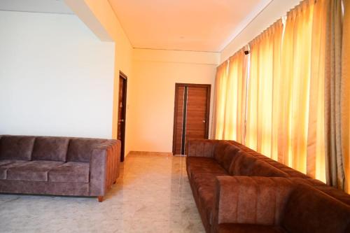 a living room with two brown couches and a window at KCG Residency in Mysore