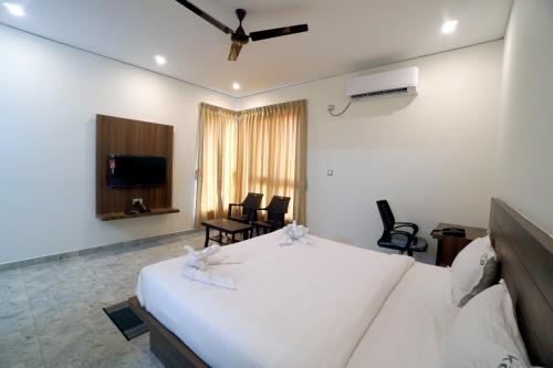 a bedroom with a white bed and a tv at KCG Residency in Mysore