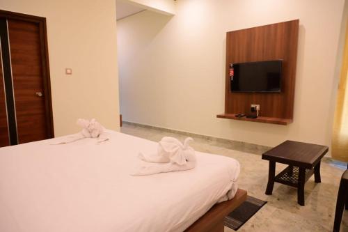 a hotel room with a bed and a tv at KCG Residency in Mysore