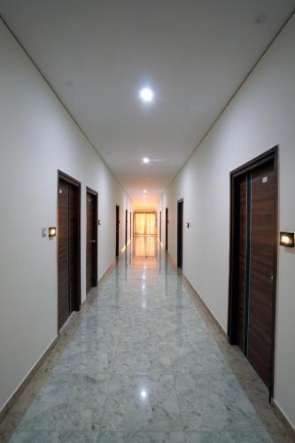 an empty hallway with doors and a tile floor at KCG Residency in Mysore
