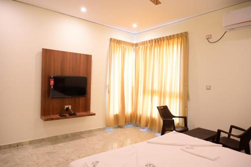 a room with two beds and a flat screen tv at KCG Residency in Mysore