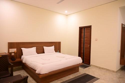 a bedroom with a bed with white sheets and a desk at KCG Residency in Mysore