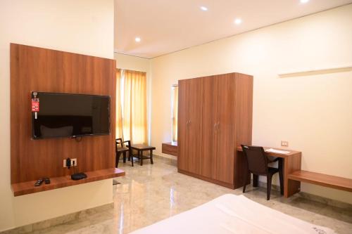 a hotel room with a tv and a desk with chairs at KCG Residency in Mysore