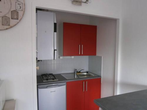 une petite cuisine avec des armoires rouges et un évier dans l'établissement Arcachon centre 300m plage 50m gare SNCF, à Arcachon