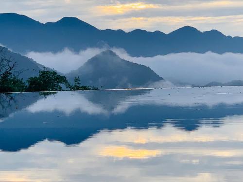 a view of a lake with mountains in the background at Amigo Pu Luong in Làng Bang