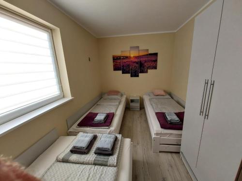 3 Betten in einem Zimmer mit Fenster in der Unterkunft domek Lawendowy na wiejskiej in Lubiatowo