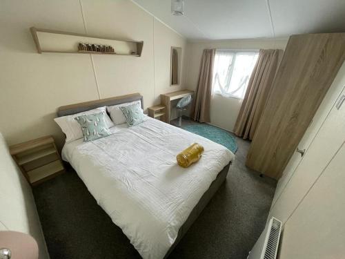 a bedroom with a bed with a yellow object on it at Modern 6 Berth Caravan With Wifi At St Osyth Beach In Essex Ref 28051fv in Clacton-on-Sea