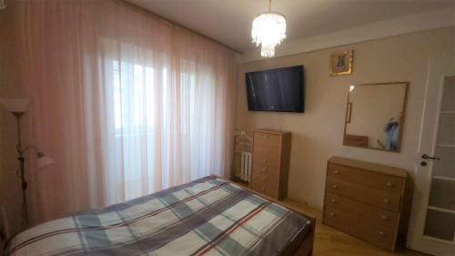 sypialnia z łóżkiem, telewizorem i oknem w obiekcie Апартаменти поруч з метро Лівобережна w Kijowie