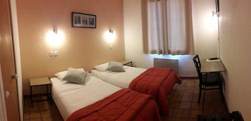 a hotel room with two beds and a desk at Hôtel Saint Michel in Digne-les-Bains