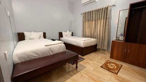 una camera d'albergo con due letti e uno specchio di PROVINCE FIVE HOTEL a Bhairāhawā