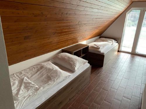 two beds in a room with a wooden wall at Chata Holiday in Bítov