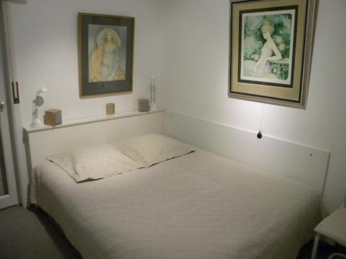 1 dormitorio con 1 cama blanca y 2 cuadros en la pared en Atlantic 0635, en Koksijde