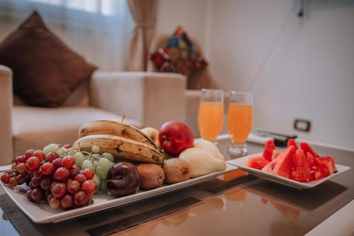 a tray of fruit on a table with two glasses of orange juice at Swiss Royal DAHAB in Dahab
