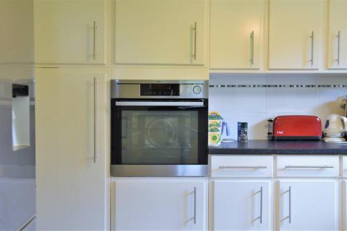 une cuisine avec des armoires blanches et un four à plaques de cuisson dans l'établissement Villa Sea, Surf & Golf - Saubion - Hossegor, à Saubion