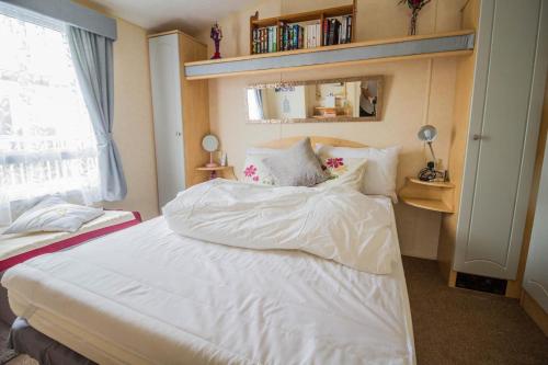 a bedroom with a white bed and a window at Lovely 6 Berth Caravan With Decking To The Side In Heacham Ref 21009i in Heacham