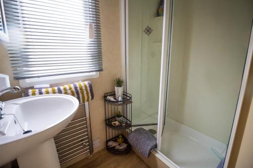 a bathroom with a white sink and a shower at Lovely 6 Berth Caravan With Decking To The Side In Heacham Ref 21009i in Heacham