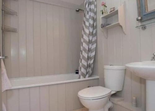 a bathroom with a toilet and a tub and a sink at The Flower House in Madron