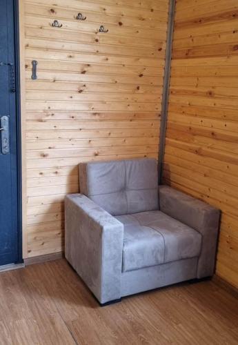 a gray couch in a room with a wooden wall at Gergeti Woods in Stepantsminda