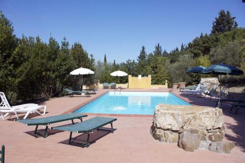 a swimming pool with two picnic tables and umbrellas at Corte Di Valle in Greve in Chianti