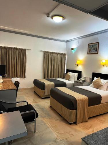 a hotel room with two beds and a table at Grand Astoria Hotel in Dubai