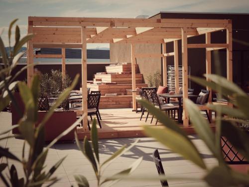 a wooden deck with chairs and a pergola at Afterwork Hotel in Etoy