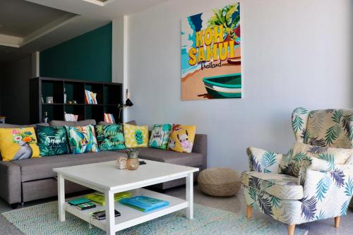 a living room with a couch and a table and a chair at The Bay Condominium, 1-bed apartment with stunning sea views in Koh Samui 