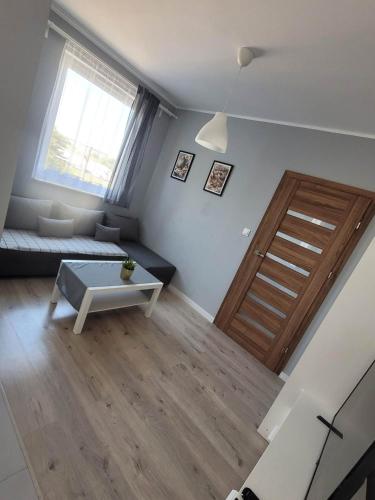 a living room with a couch and a wooden door at Apartament Słowińców 32 in Wejherowo