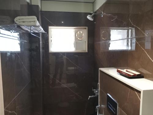 a bathroom with a shower with a glass door at Hotel Rajshree in Ahmadnagar