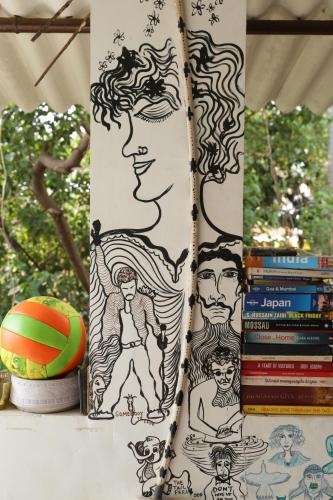 a stand with drawings on it next to a stack of books at Dreamcatcher House & Hostel at Arambol Beach in Arambol