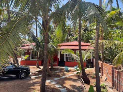 a car parked in front of a house with palm trees at Sandcastle Cottages 1 AC - Indoor Pool - WiFi - SmartTV - Parking - Diveagar in Diveagar