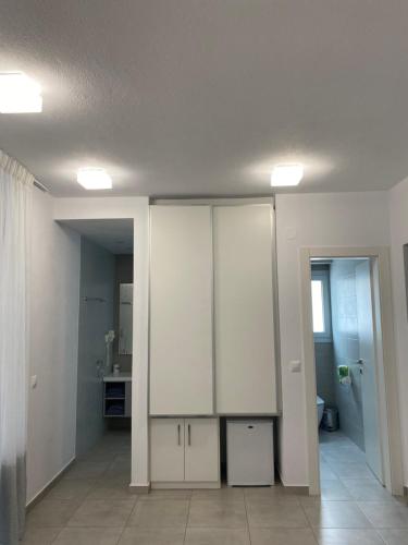 an empty room with white cabinets and a bathroom at Anemoni Beach Hotel in Skiathos Town