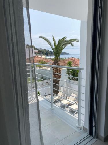 a balcony with a palm tree and a view of the ocean at Anemoni Beach Hotel in Skiathos Town