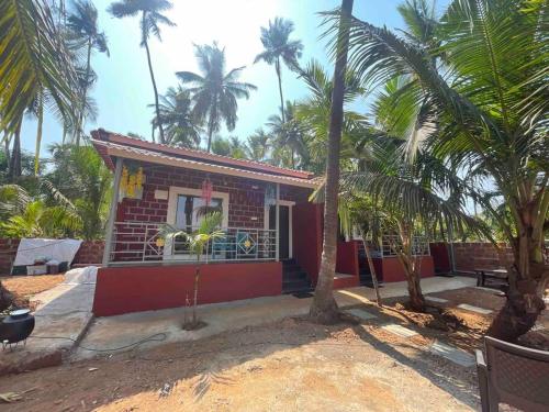a small house with palm trees in front of it at Sandcastle Cottages 1 AC - Indoor Pool - WiFi - SmartTV - Parking - Diveagar in Diveagar