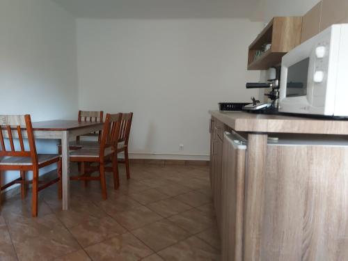 a kitchen with a table with chairs and a microwave at Potyka Apartman in Tiszafüred