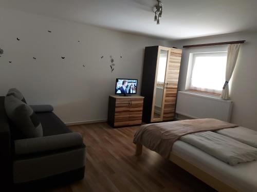 1 dormitorio con cama, sofá y TV en Potyka Apartman, en Tiszafüred