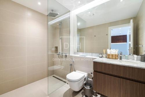 a bathroom with a toilet and a glass shower at Modern 1 Bed Sea View Le Pont B1 La Mer in Dubai