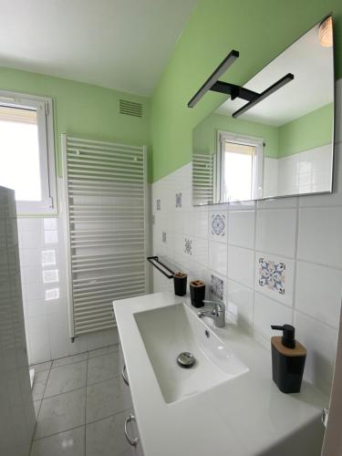 uma casa de banho com um lavatório branco e um espelho. em Gîte aux portes des châteaux - 12 min de Beauval em Saint-Romain-sur-Cher
