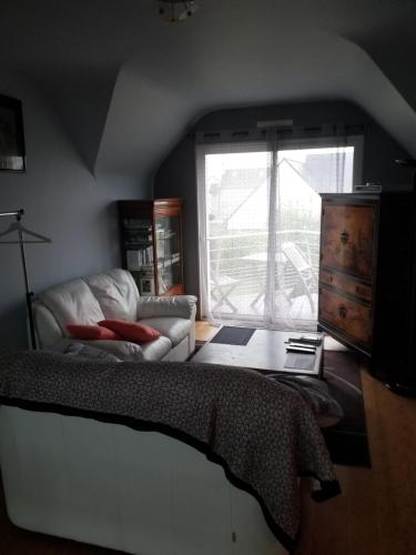 1 dormitorio con cama, sofá y ventana en Ker Kistin, en Fouesnant