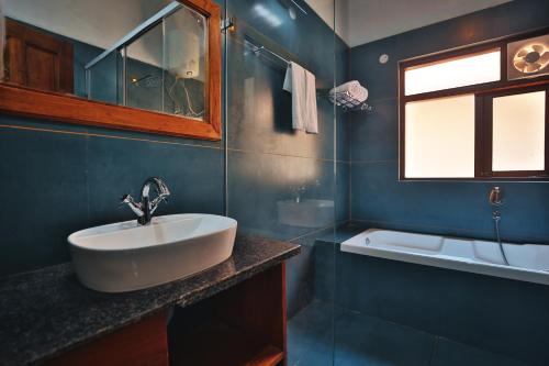 a bathroom with a sink and a tub and a window at Hill Crest Resort - Coorg in Madikeri