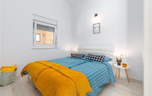 ein Schlafzimmer mit einem Bett mit blauer Decke und einem Fenster in der Unterkunft Nice Home In Betiga With Sauna, Outdoor Swimming Pool And Jacuzzi in Barbariga