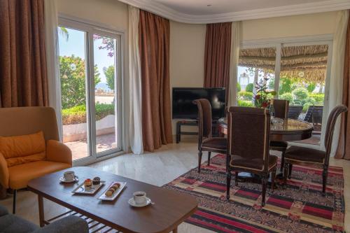 uma sala de estar com uma mesa e cadeiras e uma televisão em Sharm Club Beach Resort em Sharm el Sheikh