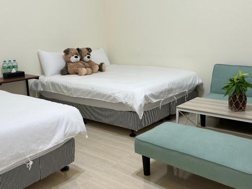 a teddy bear sitting on a bed in a bedroom at Xinzhan 23 B&B in Taitung City