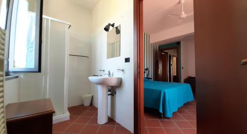 uma casa de banho com um lavatório e uma cama num quarto em Agriturismo Calendiluna em Luni