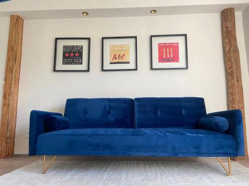 un sofá azul en una sala de estar con tres posters enmarcados en Stilvolles Apartment mit Sauna, en Burg